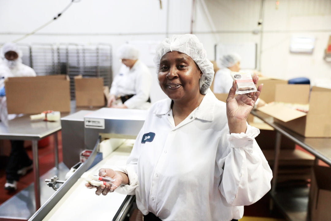 Greyston Bakery employee working in the bakery and holding an individually wrapped brownie